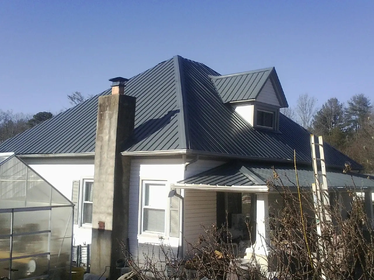 Dark blue standing seam metal roof on a white farmhouse with dormer — Slate & Tile Roof Repair by Roofing Brothers in West Decatur
