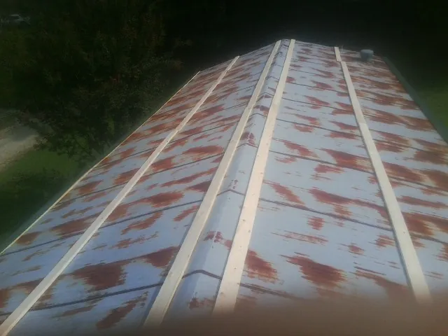 Rusted metal roof panels with new wood purlins before replacement — Storm Damage Roof Repair in West Decatur by Roofing Brothers