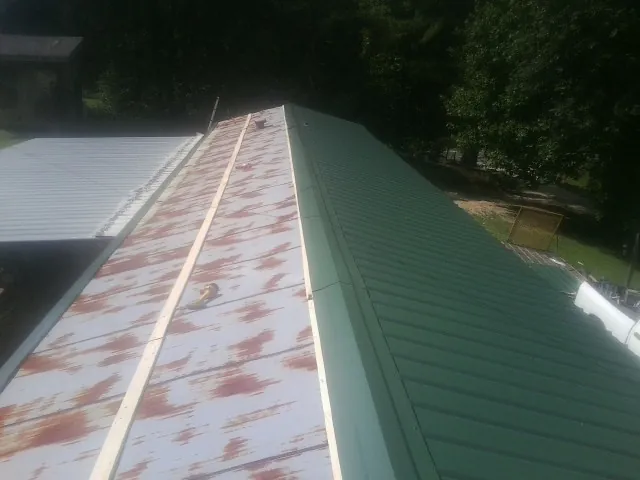 Old rusted panels beside newly installed green metal roofing — Wind Damage Roof Repair by Roofing Brothers in West Decatur