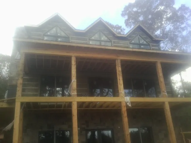 Dormers and porch framing on a large log home under construction — Roof Coating work by our crew in West Decatur