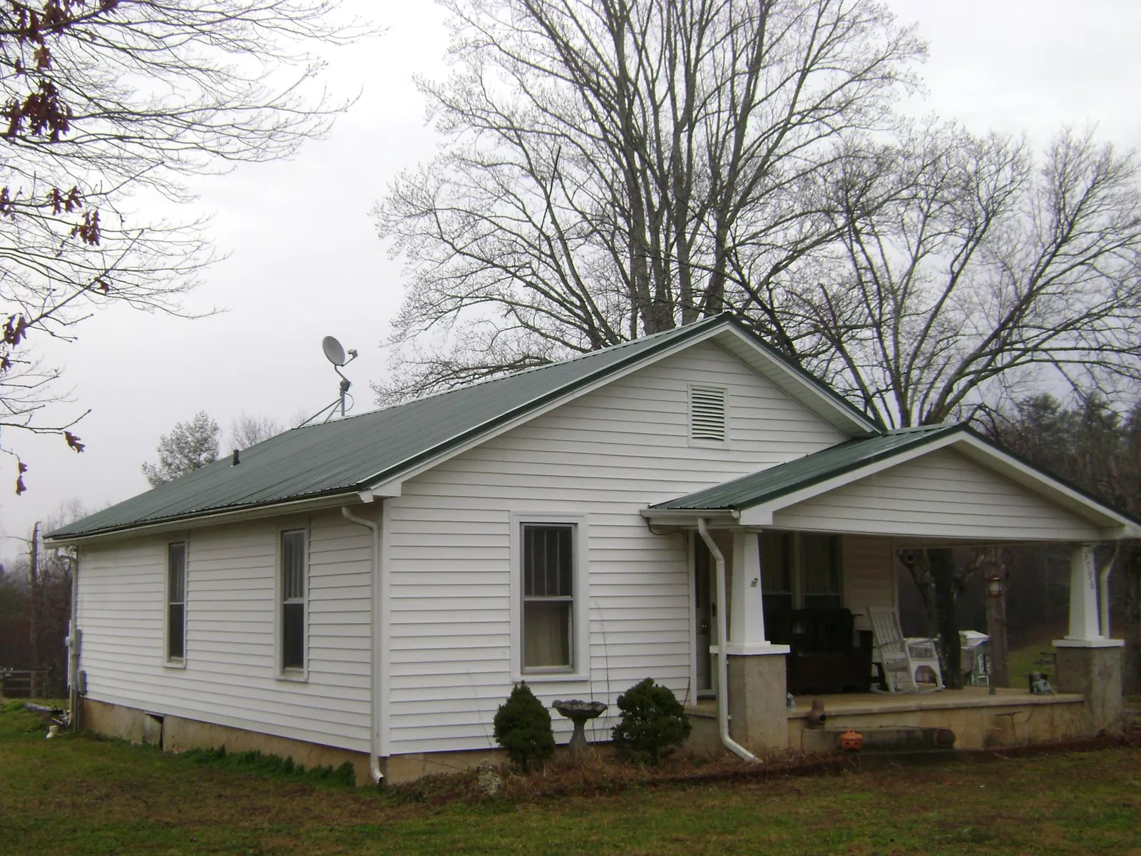 Green metal roof on a white bungalow with a side porch in West Decatur