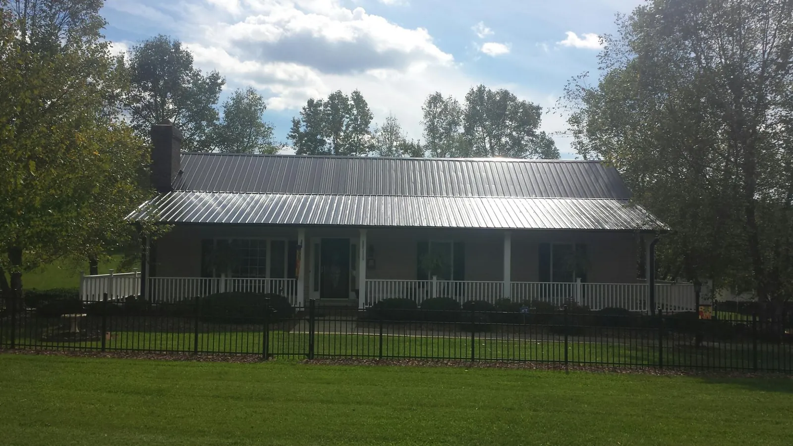 Gray metal roof on a brick ranch with a full width front porch — Gutter Guard Installation work by our crew in West Decatur