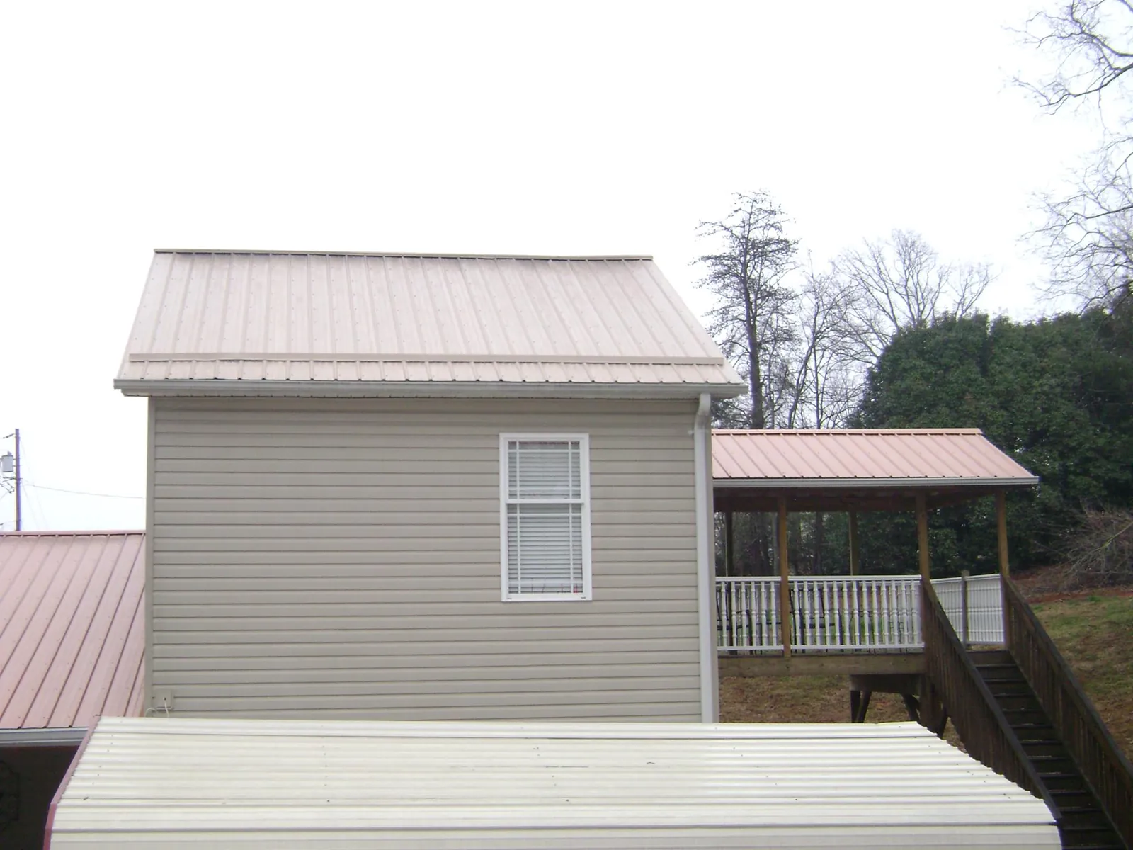 Tan metal roofs on a two story addition and attached porch, from a Roof Replacement job in West Decatur