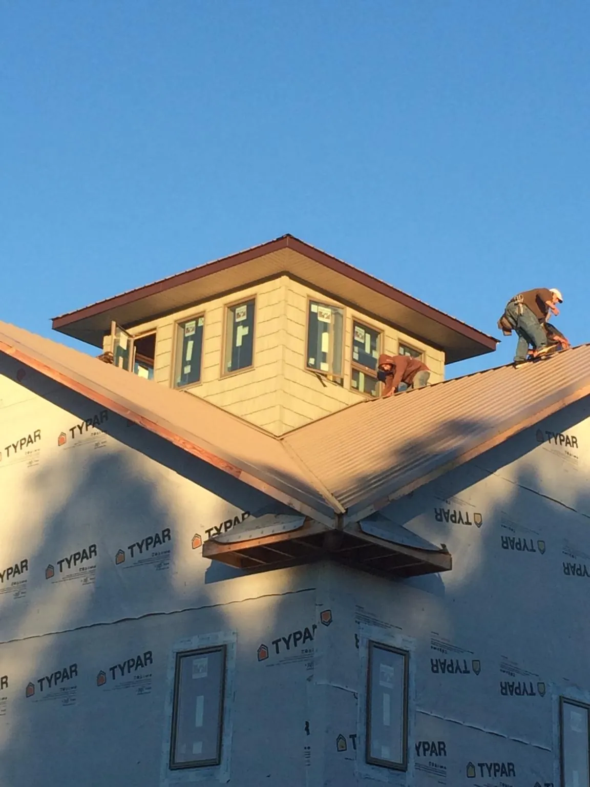 Roofers working around a rooftop cupola on a new metal roof at sunset — Roof Waterproofing in West Decatur by Roofing Brothers